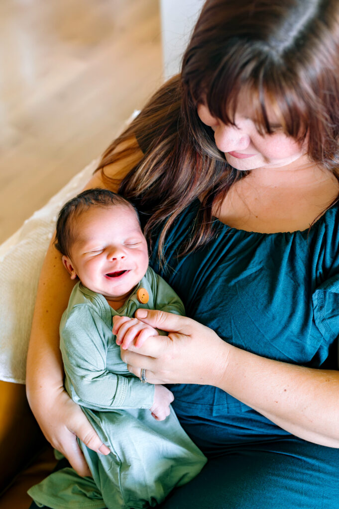 Mother holding her newborn baby during an in-home McKinney newborn photography session, capturing a peaceful and emotional newborn moment.