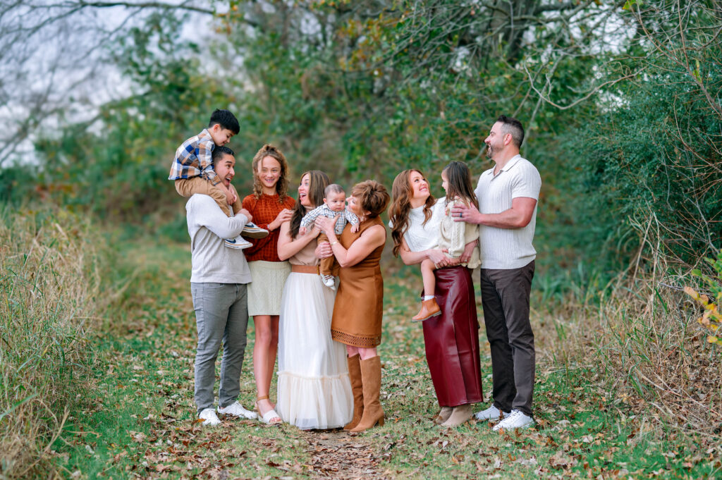 Large extended family standing together on a wooded path during a coordinated fall family photo session at Erwin Park in McKinney.
