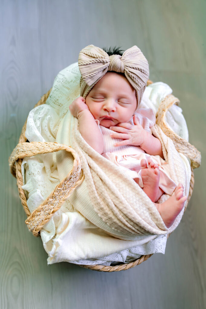 Newborn girl with neutral colors on wrapped asleep in basket for her in home lifestyle newborn session in McKinney, Texas, by a McKinney Newborn Photographer.