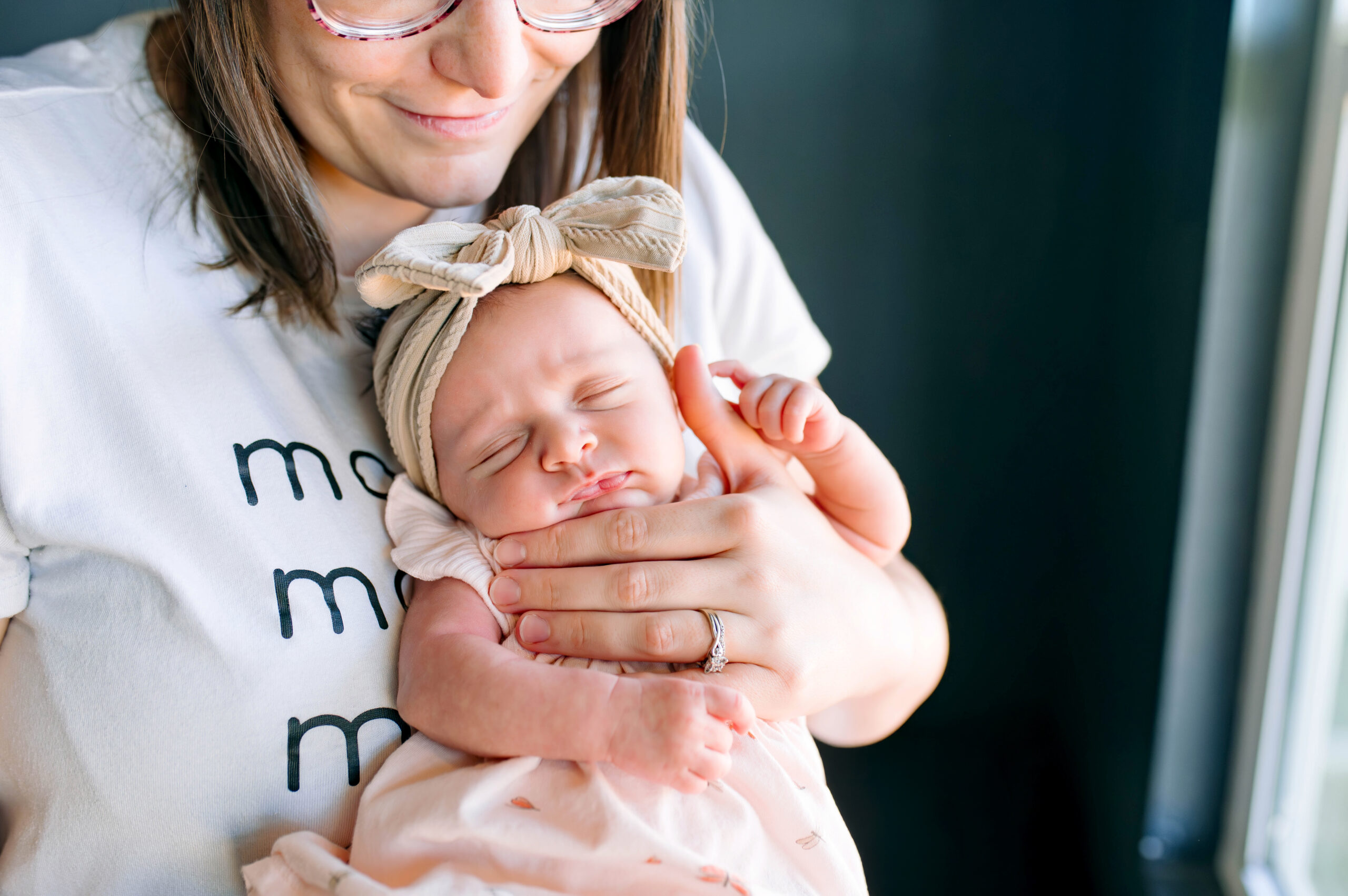 Mom holding newborn daughter for their in home lifestyle newborn session in McKinney, Texas, by a McKinney Newborn Photographer.
