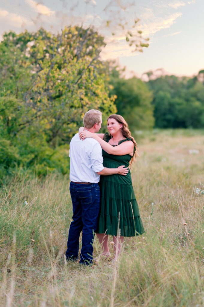 McKinney maternity photographer capturing pregnant mom and dad in field at Arbor Hills for a maternity session in Plano, Texas.