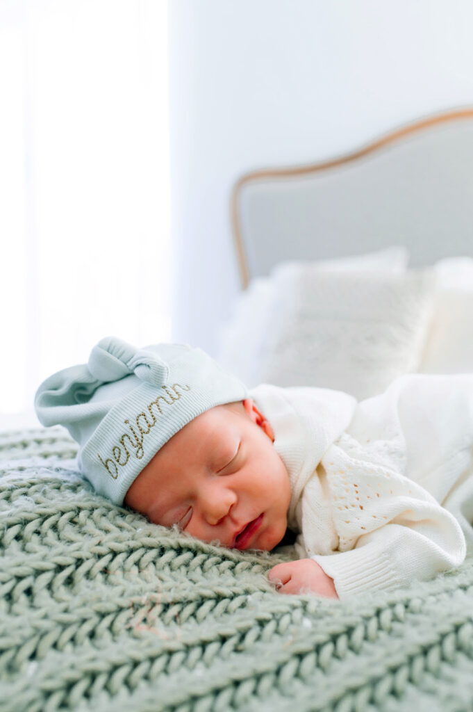 McKinney newborn photographer capturing newborn boy on bed on top of a green blanket in a bright studio for their newborn session in McKinney, Texas.