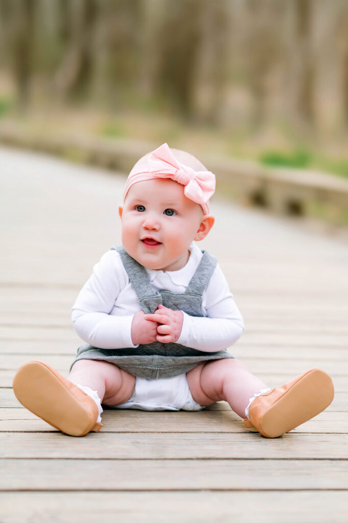 Baby girl sitting on wooden walkway at Oak Point Park in Plano, Texas with Jennifer L Kirk Photography.