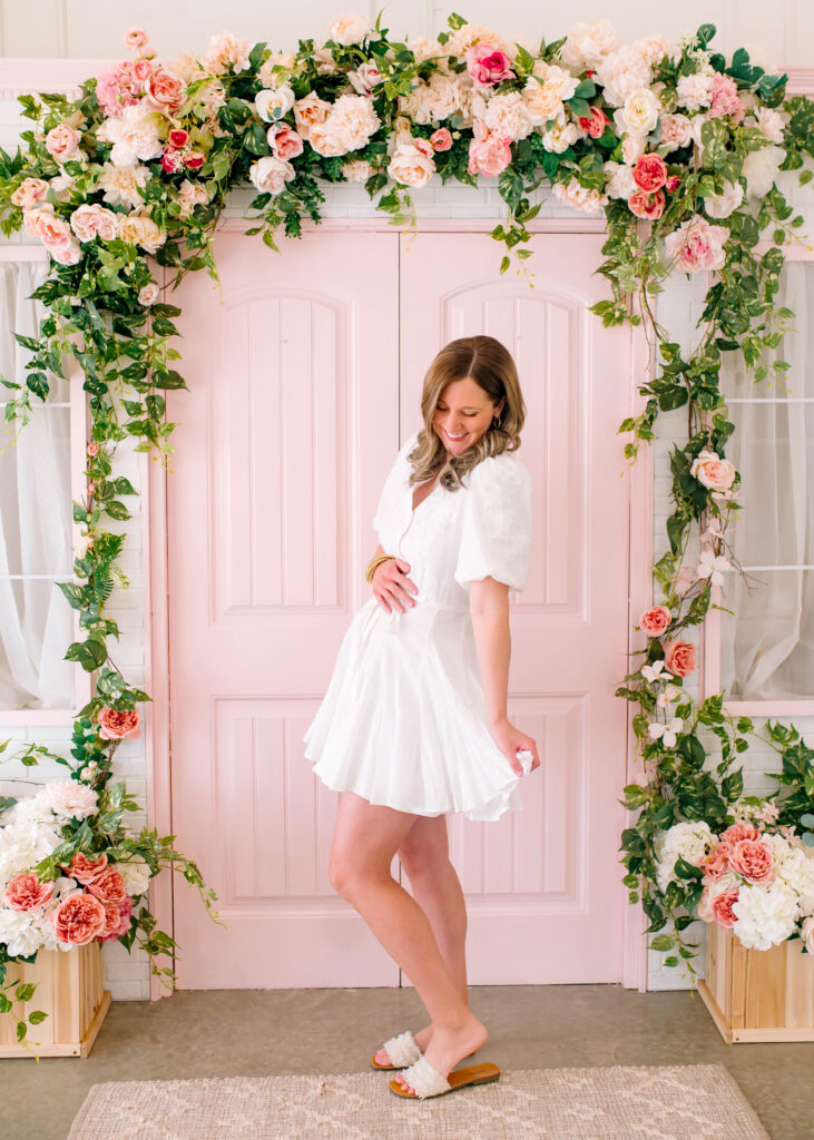Mother posing and laughing while holding her baby belly during a birth announcement session at Lemon Drop Studios in McKinney, Texas.